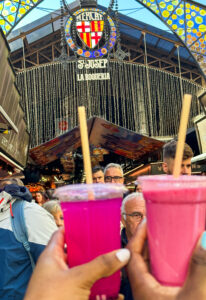 Photo of the famous fresh juices from Mercado de la Boqueria in Barcelona, Spain. The juices are pink. Food to try in Barcelona.