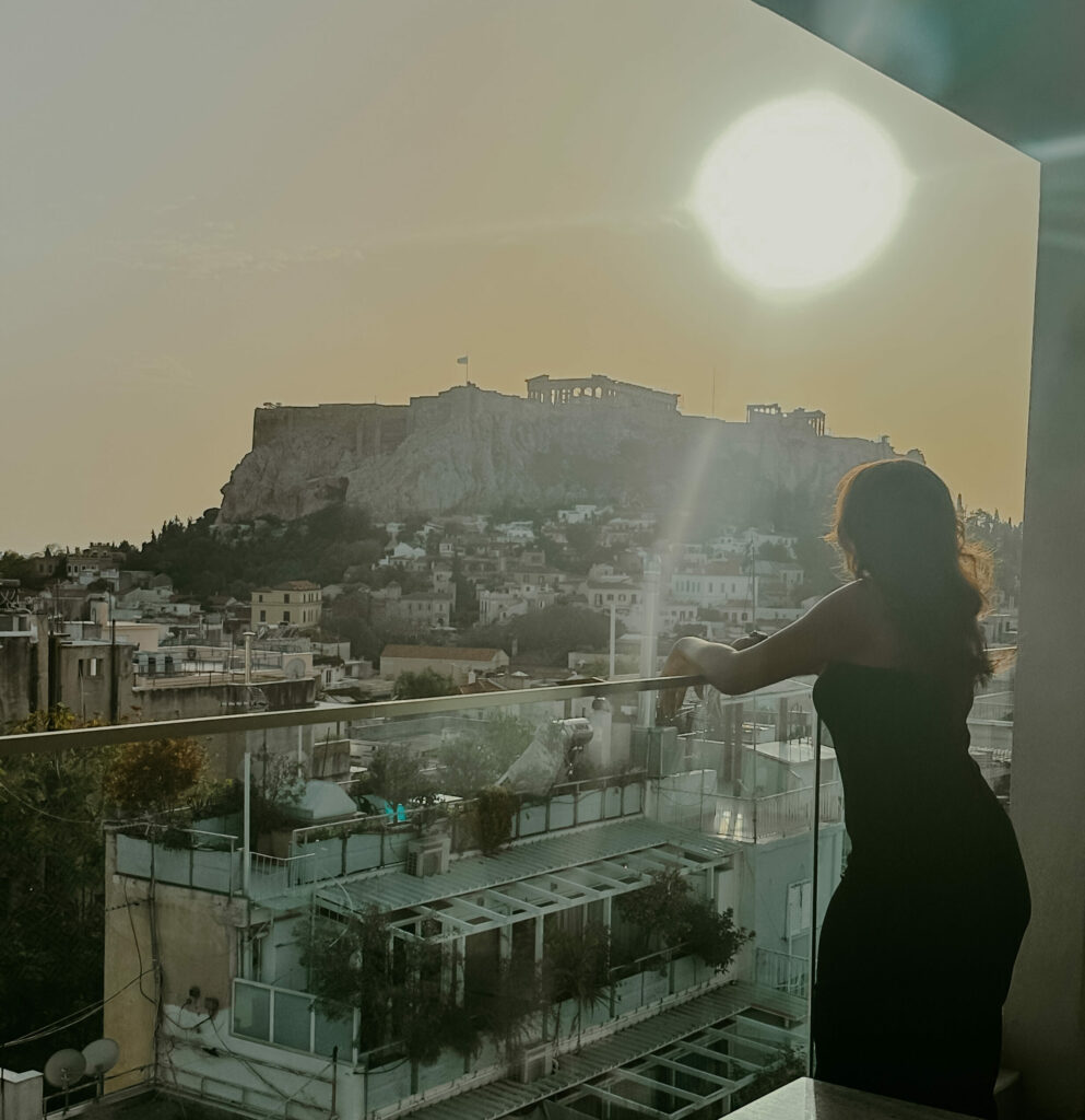 Woman on balcony in Athens with a view of The Acropolis.